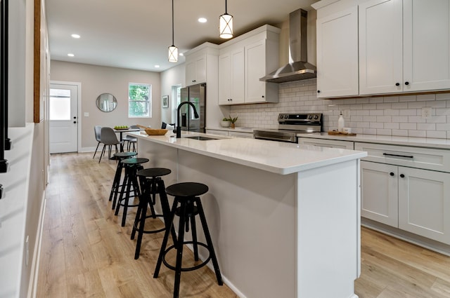 2589 Dayton Ave, Columbus, OH 43202 - kitchen with stainless steel appliances, wall chimney exhaust hood, a sink, a kitchen bar, and a kitchen island with sink