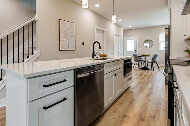 2589 Dayton Ave, Columbus, OH 43202 - kitchen featuring dishwasher, a sink, light wood-type flooring, white cabinetry, and decorative light fixtures