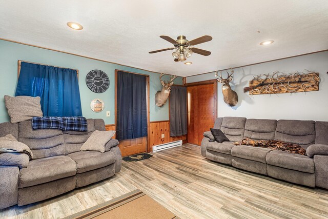 14552 Snyder Rd, Richwood, OH 43344 - living room with baseboard heating, a ceiling fan, wainscoting, wood finished floors, and wooden walls