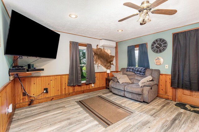 14552 Snyder Rd, Richwood, OH 43344 - living room with wainscoting, a wall unit AC, wood walls, wood finished floors, and a ceiling fan