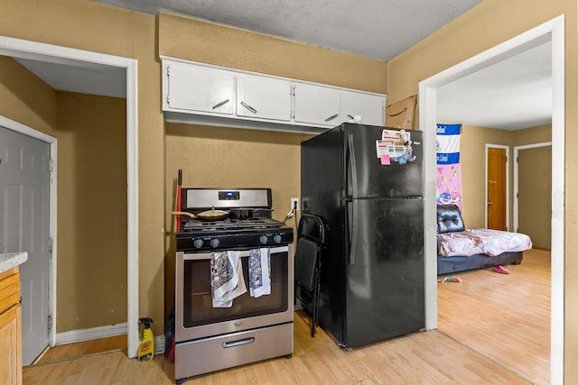 1847 Agler Rd, Columbus, OH 43224 - kitchen featuring freestanding refrigerator, stainless steel gas range, light wood finished floors, white cabinetry, and light countertops