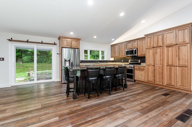 2914 Hickory Hill Dr SE, Lancaster, OH 43130 - kitchen featuring appliances with stainless steel finishes, wood finished floors, a center island, backsplash, and lofted ceiling