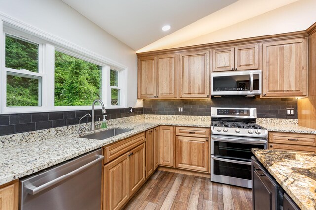 2914 Hickory Hill Dr SE, Lancaster, OH 43130 - kitchen featuring appliances with stainless steel finishes, a sink, lofted ceiling, wood finished floors, and decorative backsplash