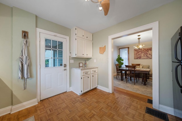 297 E Welch Ave, Columbus, OH 43207 - kitchen featuring white cabinets, baseboards, freestanding refrigerator, and a chandelier
