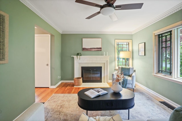 2314 Woodstock Rd, Columbus, OH 43221 - living area with wood finished floors, a brick fireplace, ornamental molding, a ceiling fan, and baseboards
