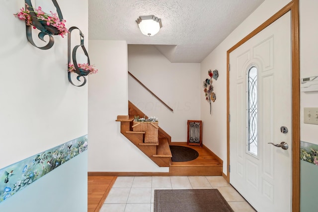 5046 Rolling Rock Ct, Columbus, OH 43229 - foyer entrance featuring stairs, a textured ceiling, light tile patterned flooring, and baseboards