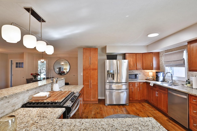 7775 Pembrook Dr, Reynoldsburg, OH 43068 - kitchen with appliances with stainless steel finishes, a sink, light wood-style floors, brown cabinets, and light stone countertops