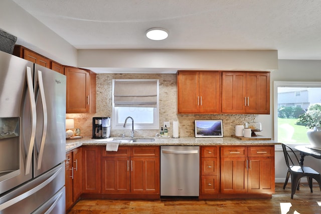 7775 Pembrook Dr, Reynoldsburg, OH 43068 - kitchen with stainless steel appliances, a sink, light wood-style floors, and brown cabinetry