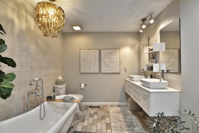 7775 Pembrook Dr, Reynoldsburg, OH 43068 - full bath featuring a textured ceiling, a freestanding tub, toilet, double vanity, and a chandelier