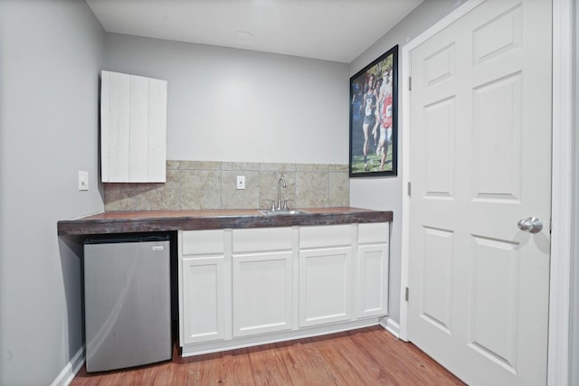 336 Saint Thomas Dr, Westerville, OH 43081 - kitchen featuring refrigerator, a sink, dark countertops, light wood-style flooring, and white cabinetry