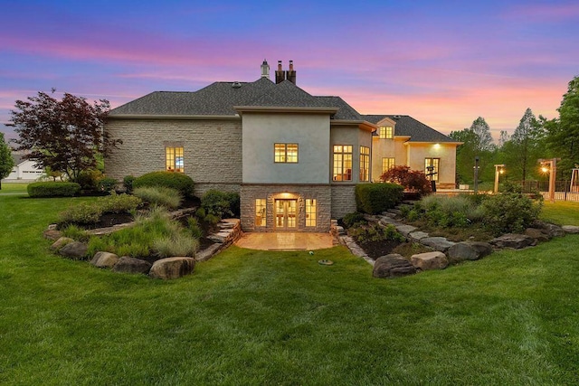 2989 Old Path Rd, Blacklick, OH 43004 - back of property at dusk with french doors, stucco siding, stone siding, a lawn, and a patio area