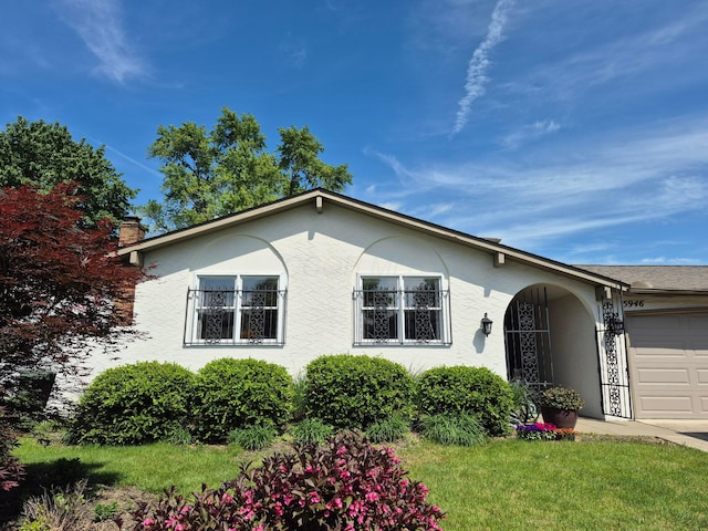 5946 Lisa St, Columbus, OH 43231 - single story home with stucco siding, an attached garage, a chimney, and a front lawn