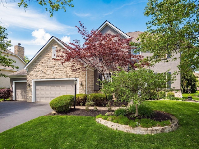 6628 Dalmore Ln, Dublin, OH 43016 - view of property hidden behind natural elements featuring stone siding, a front yard, driveway, and an attached garage