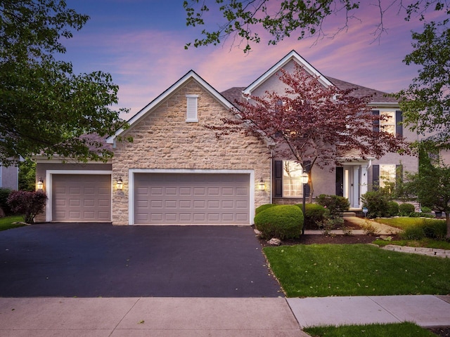 6628 Dalmore Ln, Dublin, OH 43016 - view of front facade with asphalt driveway, stone siding, a garage, and stucco siding