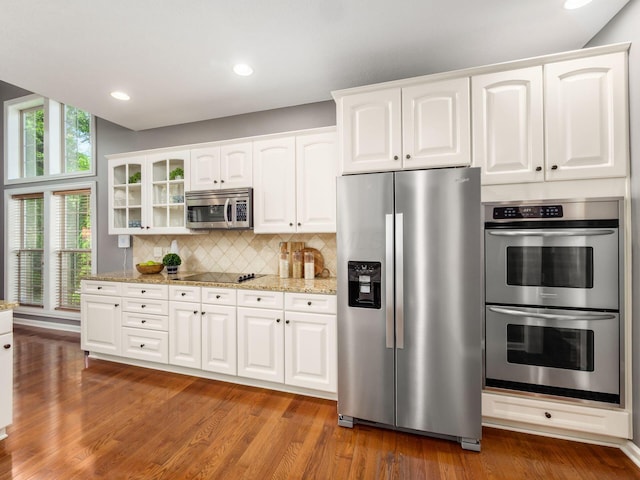 6628 Dalmore Ln, Dublin, OH 43016 - kitchen featuring stainless steel appliances, glass insert cabinets, light stone counters, decorative backsplash, and recessed lighting