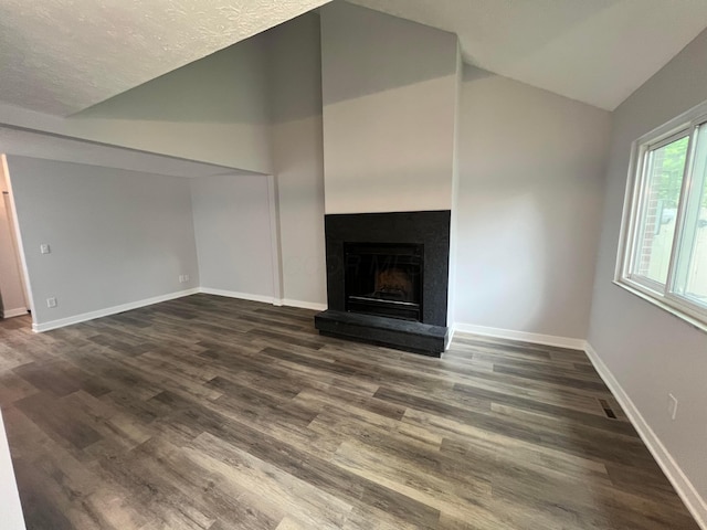 139 Corbins Mill Dr, Dublin, OH 43017 - unfurnished living room featuring lofted ceiling, dark wood-style floors, a fireplace with raised hearth, baseboards, and a textured ceiling