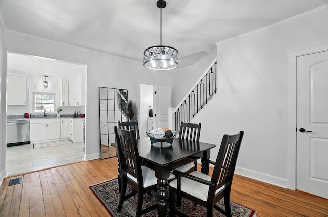 446 E Beck St, Columbus, OH 43206 - dining space with light wood-style floors, a chandelier, baseboards, ornamental molding, and stairway