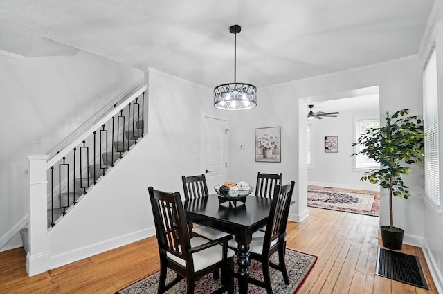 446 E Beck St, Columbus, OH 43206 - dining room with stairway, light wood finished floors, baseboards, a chandelier, and crown molding