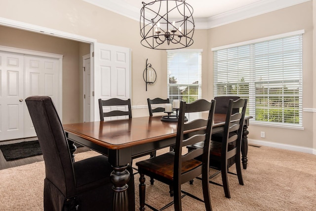 dining room with a chandelier, ornamental molding, baseboards, and light colored carpet