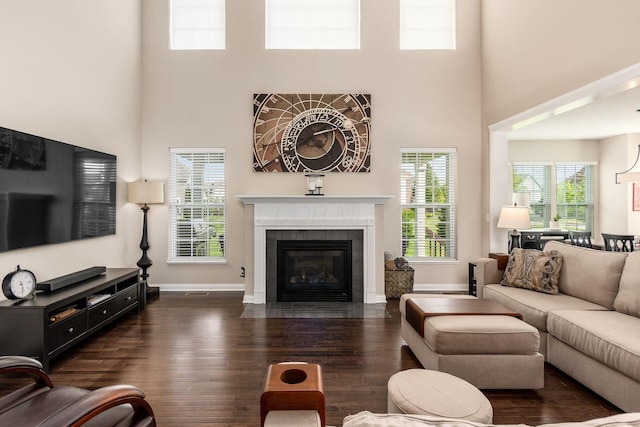 living room with a high ceiling, wood finished floors, baseboards, and a tile fireplace