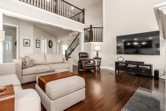 living room with hardwood / wood-style flooring, a towering ceiling, stairway, and baseboards