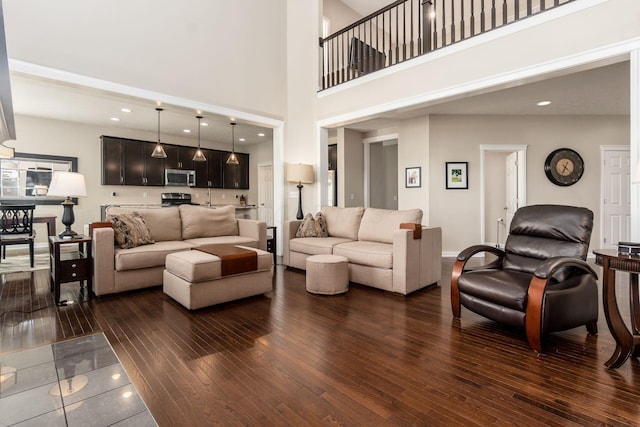 living area featuring dark wood-type flooring and a towering ceiling