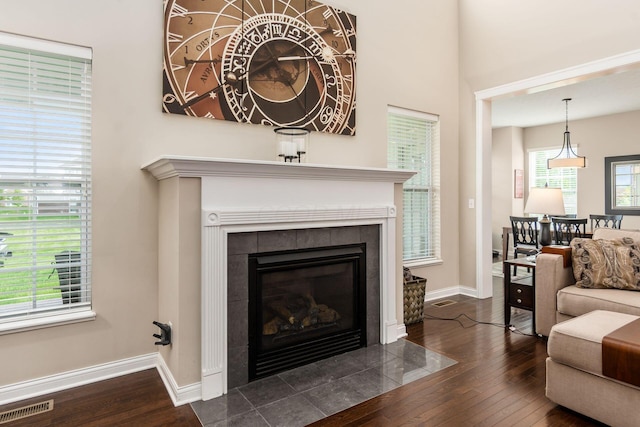 living area with dark wood-type flooring, baseboards, and a fireplace