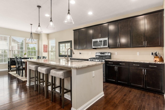kitchen with a sink, stainless steel appliances, dark wood-style flooring, recessed lighting, and a breakfast bar area