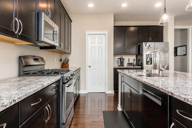 kitchen with appliances with stainless steel finishes, light stone countertops, recessed lighting, dark wood-style flooring, and pendant lighting