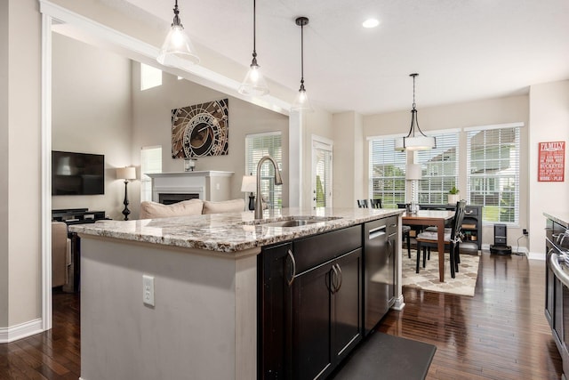 kitchen with a sink, dishwasher, baseboards, a fireplace, and dark wood-style floors