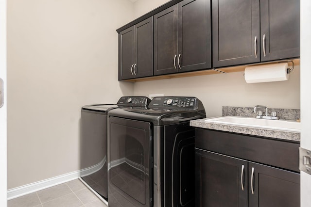 clothes washing area featuring washer and clothes dryer, cabinet space, baseboards, and light tile patterned flooring
