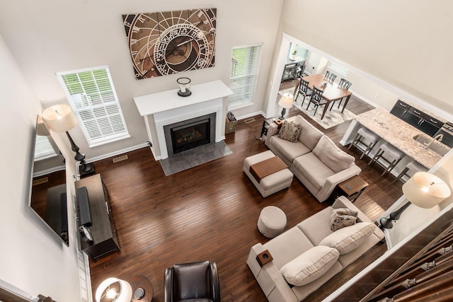 living room with wood finished floors, baseboards, and a fireplace with flush hearth