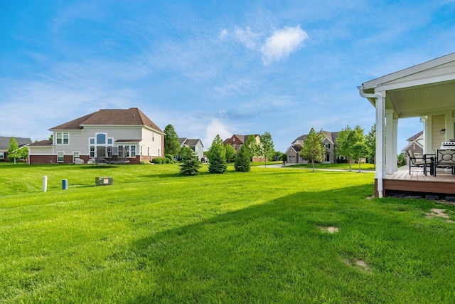 view of green lawn featuring a wooden deck and a residential view