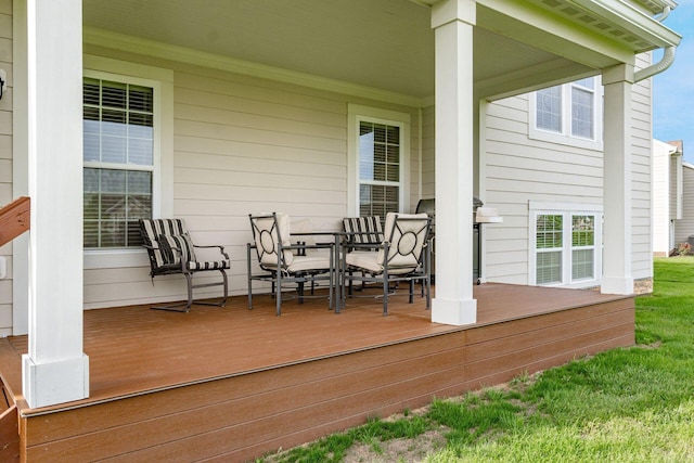 wooden deck featuring outdoor dining space, grilling area, and a lawn
