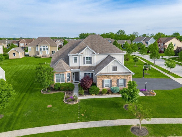 view of front of house featuring board and batten siding, a residential view, stone siding, and a front yard