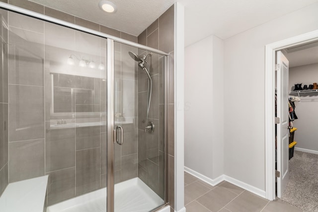 417 Oakland Hills Loop, Commercial Point, OH 43116 - bathroom with a stall shower, a walk in closet, baseboards, and tile patterned flooring