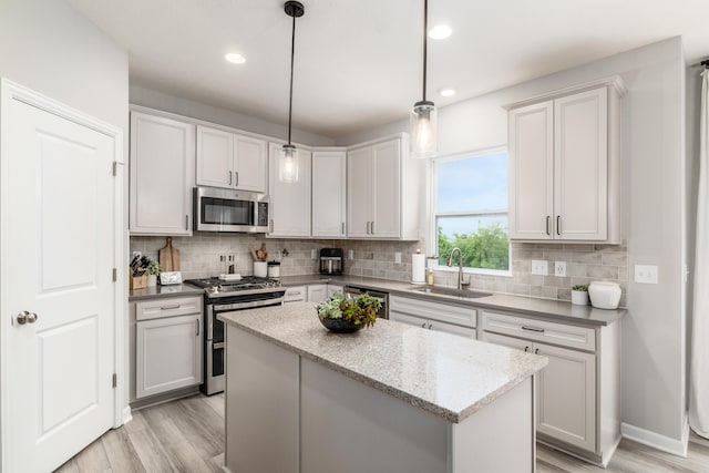 417 Oakland Hills Loop, Commercial Point, OH 43116 - kitchen featuring appliances with stainless steel finishes, a sink, light wood-style floors, backsplash, and a center island