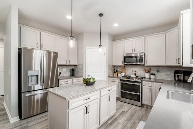 417 Oakland Hills Loop, Commercial Point, OH 43116 - kitchen featuring appliances with stainless steel finishes, a sink, light wood finished floors, a kitchen island, and decorative backsplash