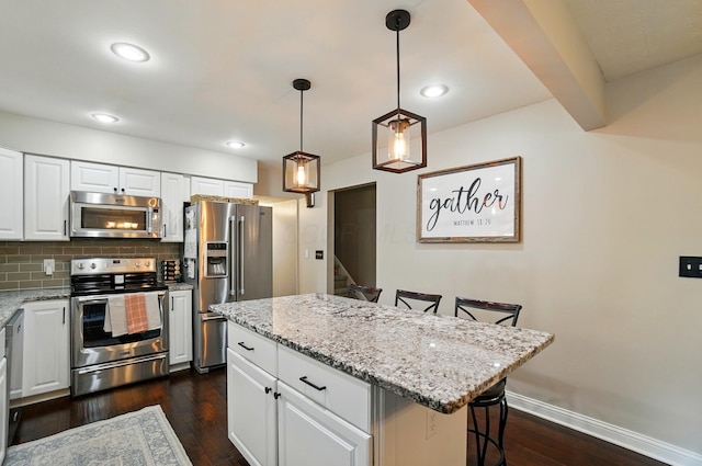 723 W Winmar Pl, Westerville, OH 43081 - kitchen with appliances with stainless steel finishes, a kitchen breakfast bar, dark wood-type flooring, light stone counters, and decorative backsplash