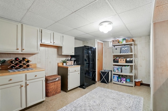 723 W Winmar Pl, Westerville, OH 43081 - kitchen with freestanding refrigerator, a paneled ceiling, light countertops, white cabinetry, and wooden walls