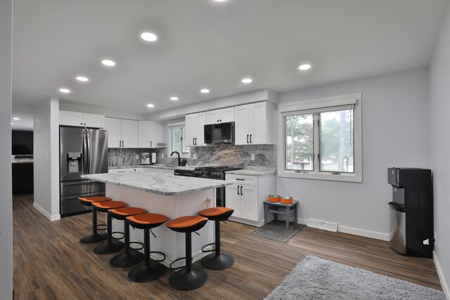327 Warlock Ct, Columbus, OH 43230 - kitchen with stainless steel appliances, white cabinetry, tasteful backsplash, a breakfast bar, and baseboards