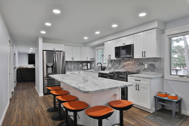 327 Warlock Ct, Columbus, OH 43230 - kitchen featuring appliances with stainless steel finishes, dark wood-type flooring, a kitchen breakfast bar, decorative backsplash, and white cabinets