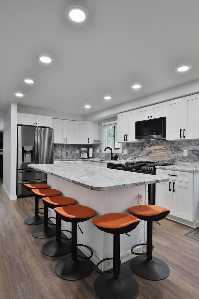 327 Warlock Ct, Columbus, OH 43230 - kitchen with appliances with stainless steel finishes, tasteful backsplash, a kitchen bar, white cabinetry, and recessed lighting
