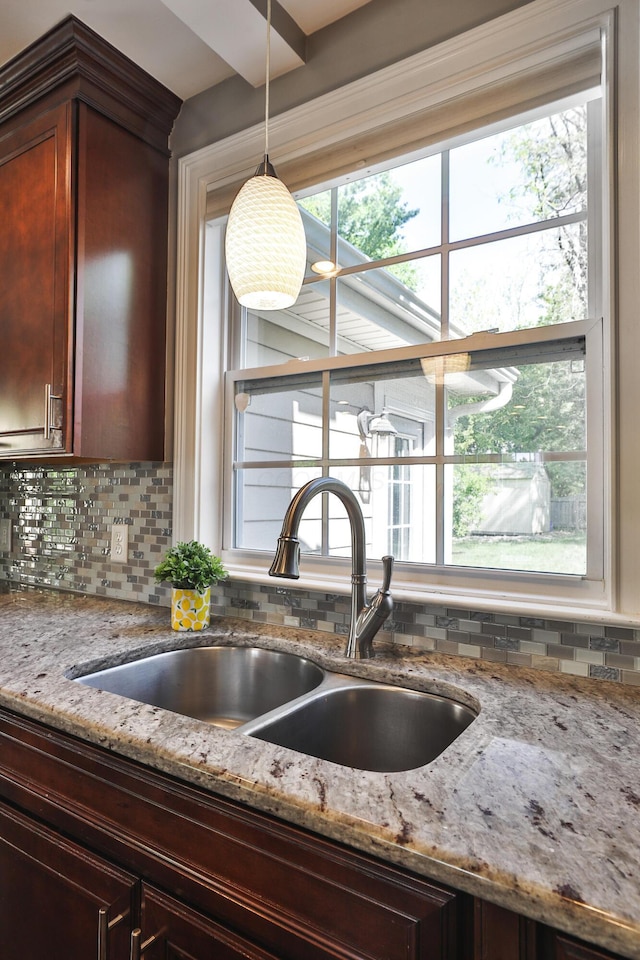 258 Canyon Dr, Columbus, OH 43214 - kitchen view of a sink, backsplash, light stone countertops, and hanging light fixtures