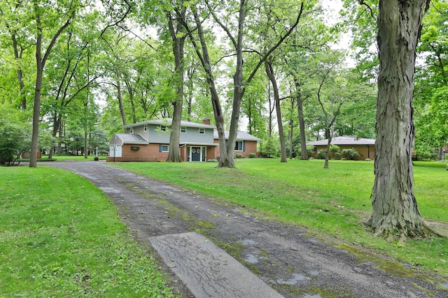 6653 Merwin Rd, Columbus, OH 43235 - view of front of property featuring brick siding, a chimney, a front yard, and driveway