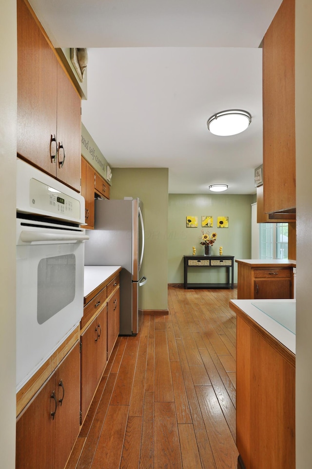 6653 Merwin Rd, Columbus, OH 43235 - kitchen with white oven, freestanding refrigerator, dark wood-style flooring, and light countertops