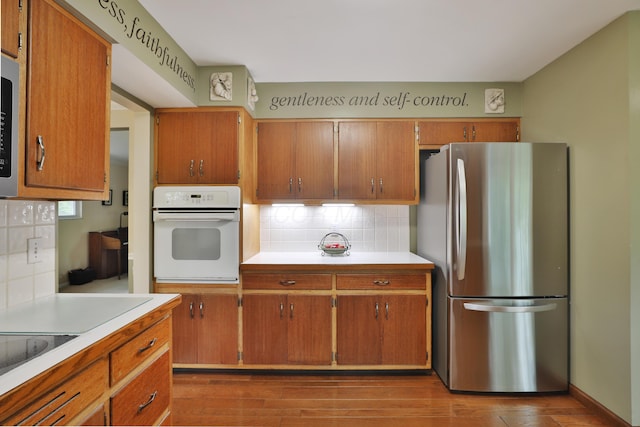 6653 Merwin Rd, Columbus, OH 43235 - kitchen with stainless steel appliances, decorative backsplash, light countertops, wood finished floors, and brown cabinetry