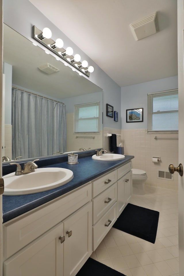 6653 Merwin Rd, Columbus, OH 43235 - bathroom featuring double vanity, tile walls, tile patterned floors, toilet, and wainscoting