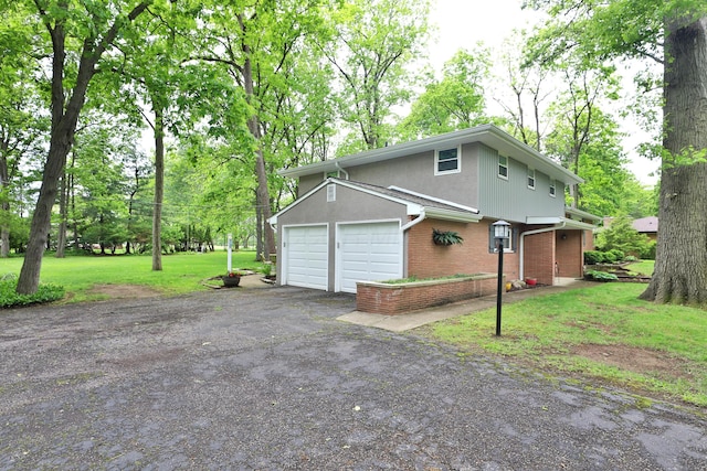 6653 Merwin Rd, Columbus, OH 43235 - view of side of home featuring brick siding, asphalt driveway, a garage, a yard, and view of scattered trees
