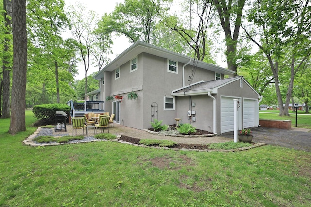 6653 Merwin Rd, Columbus, OH 43235 - rear view of property featuring an attached garage, stucco siding, asphalt driveway, and a lawn